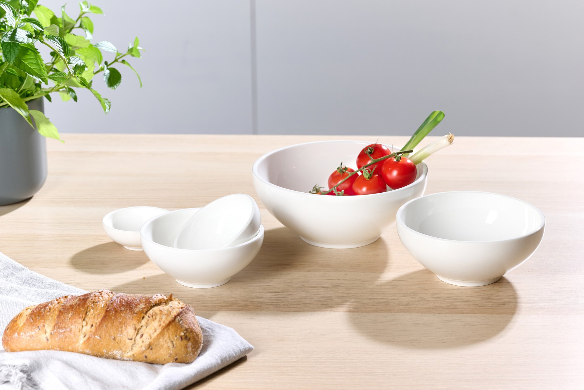 Set aus weißen Schüsseln mit Tomaten und Brot auf Tisch