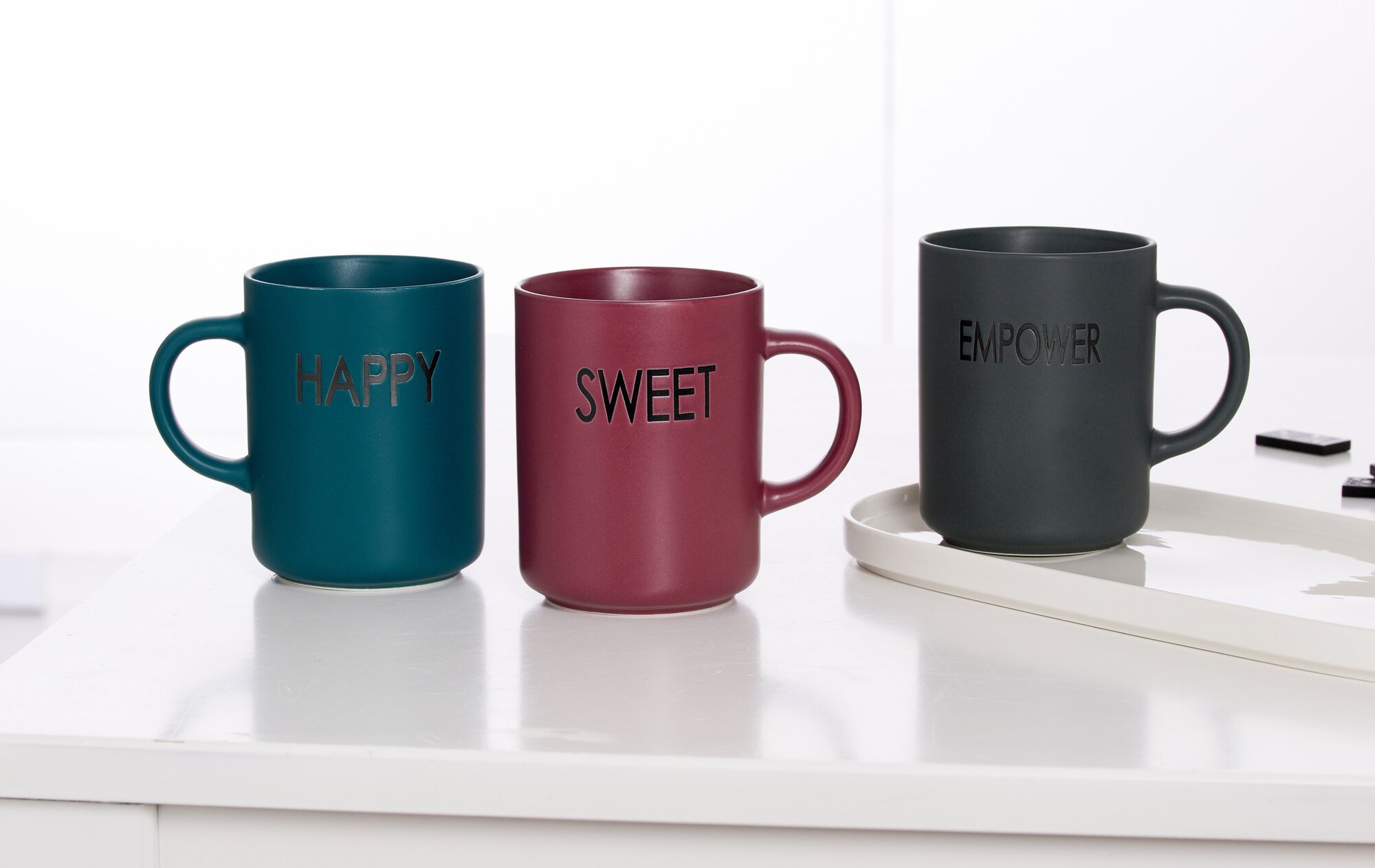 Set aus drei bunten Kaffeetassen mit Aufschriften Happy, Swe