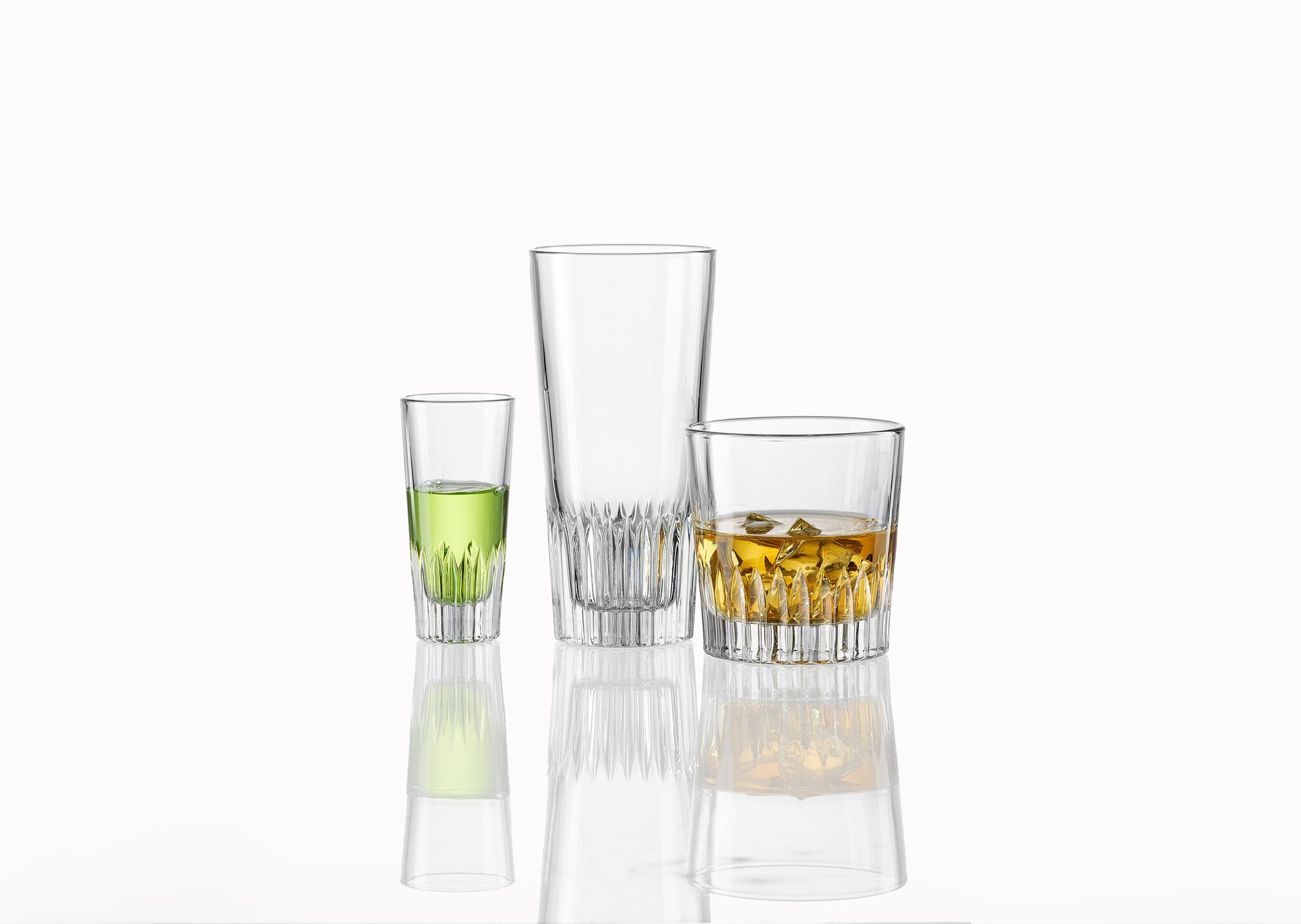 Drei Gläser mit grünem Likör, leer und Whiskey mit Eis