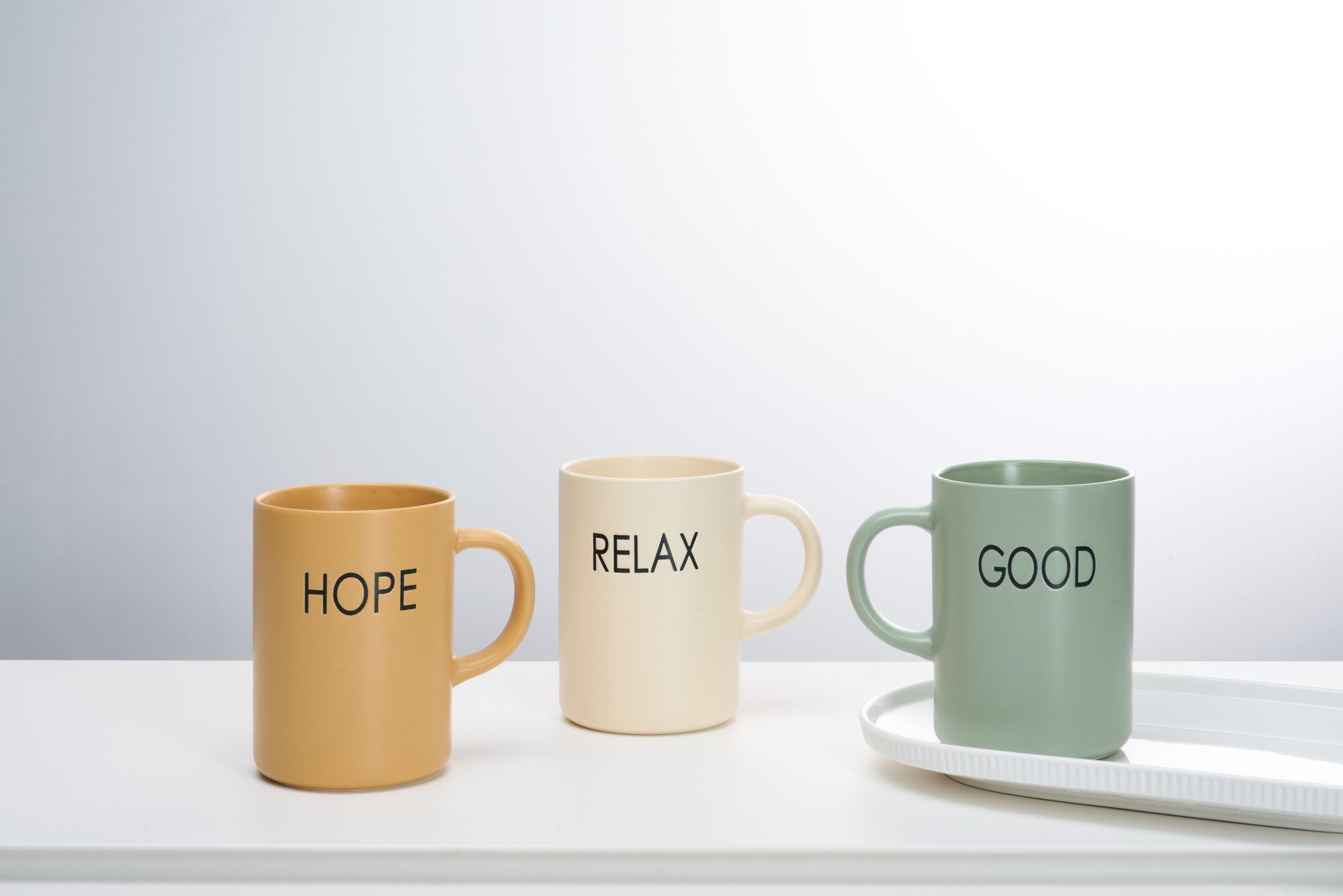 Drei bunte Keramiktassen mit HOPE, RELAX und GOOD Schrift