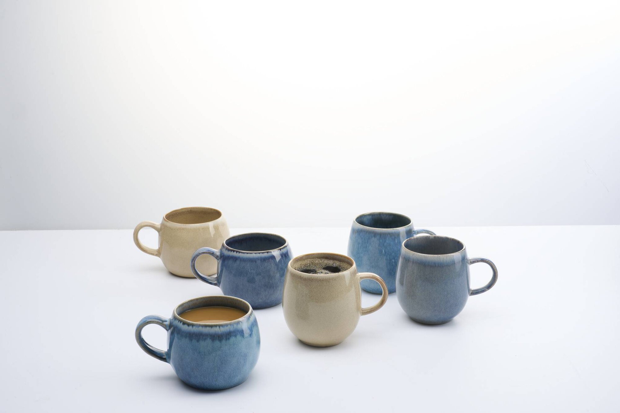 Sechs Keramik Kaffeetassen in Blau und Beige auf weißem Hint