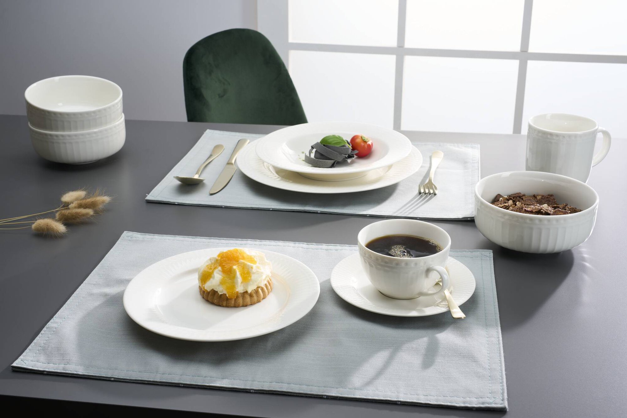Weißes Geschirr mit Kaffee, Gebäck und Besteck auf Tisch