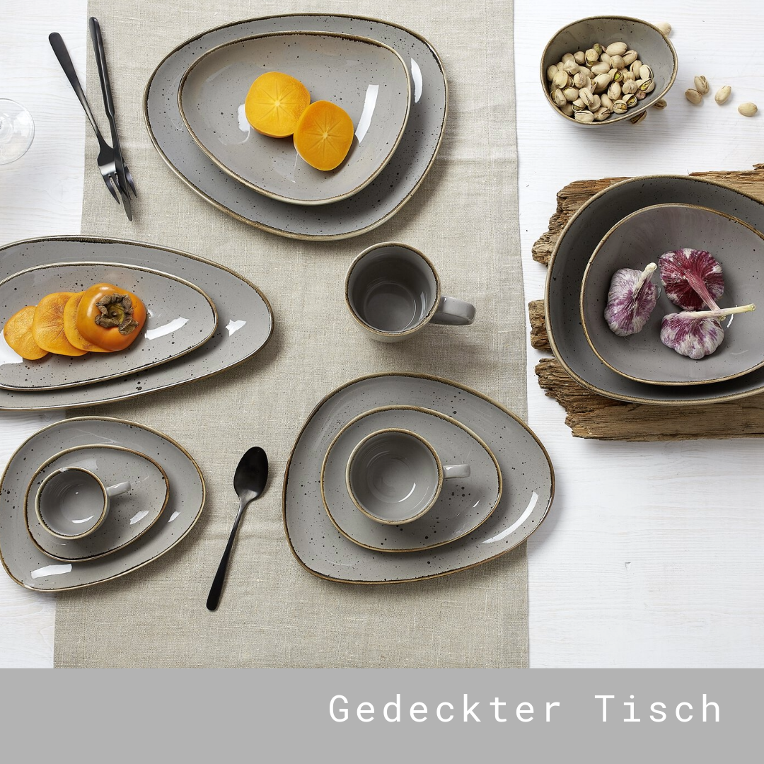 Tisch mit grauem Porzellangeschirr und Obst dekoriert