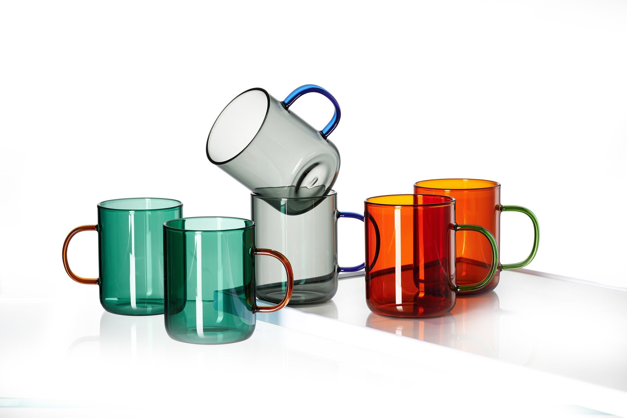 Set mit bunten Glasmuggen aus durchsichtigem Glas und farbig