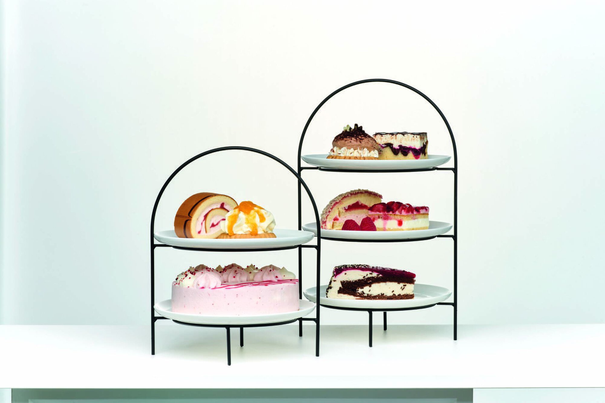 Metall-Etagere mit Tortenstücken und Sahnedesserts auf weiße